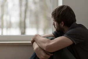 Man sitting alone by a window while struggling to overcome depression